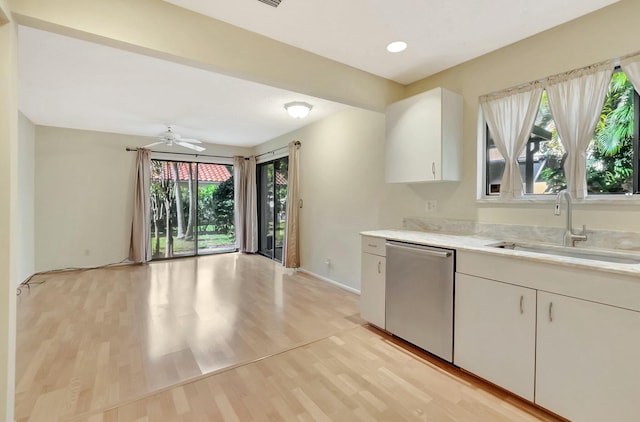 kitchen with white cabinetry, light wood finished floors, a sink, light countertops, and dishwasher