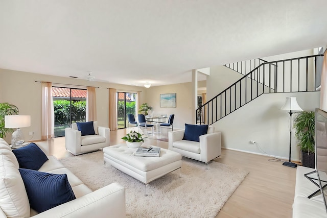 living room featuring stairway, wood finished floors, and baseboards