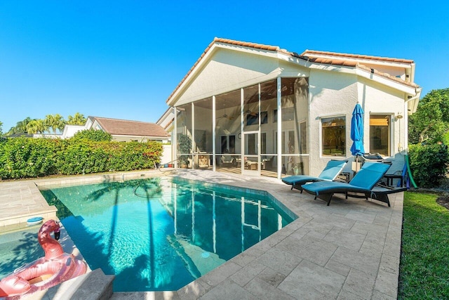 rear view of property with a patio area, a fenced in pool, a tile roof, and a sunroom