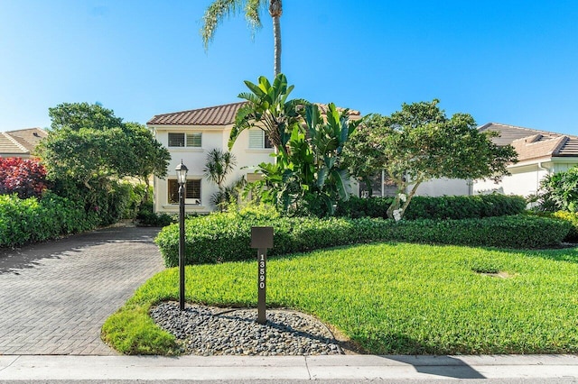 mediterranean / spanish-style house featuring stucco siding, decorative driveway, a front lawn, and a tile roof