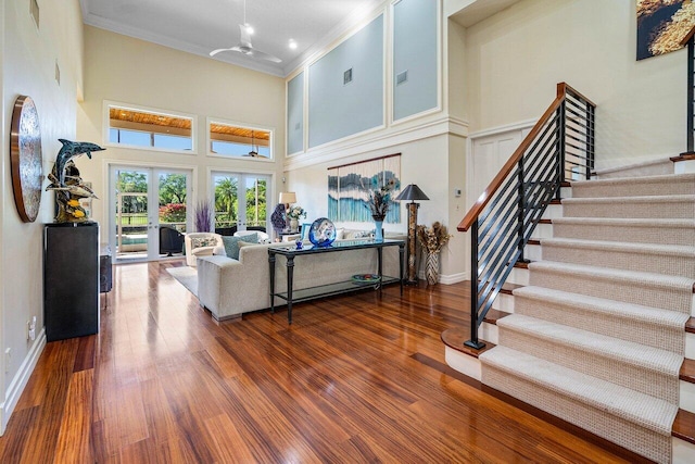 living room featuring crown molding, baseboards, stairway, wood finished floors, and a ceiling fan