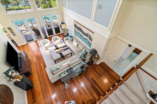 living area with french doors, wood finished floors, visible vents, and a towering ceiling