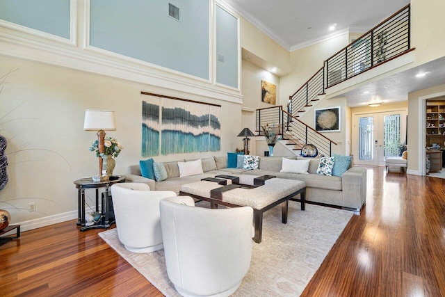 living area with visible vents, wood finished floors, stairs, and crown molding