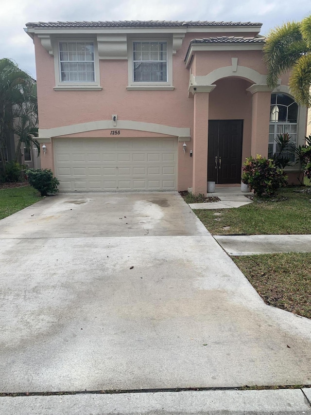 view of front facade featuring stucco siding, driveway, and a garage