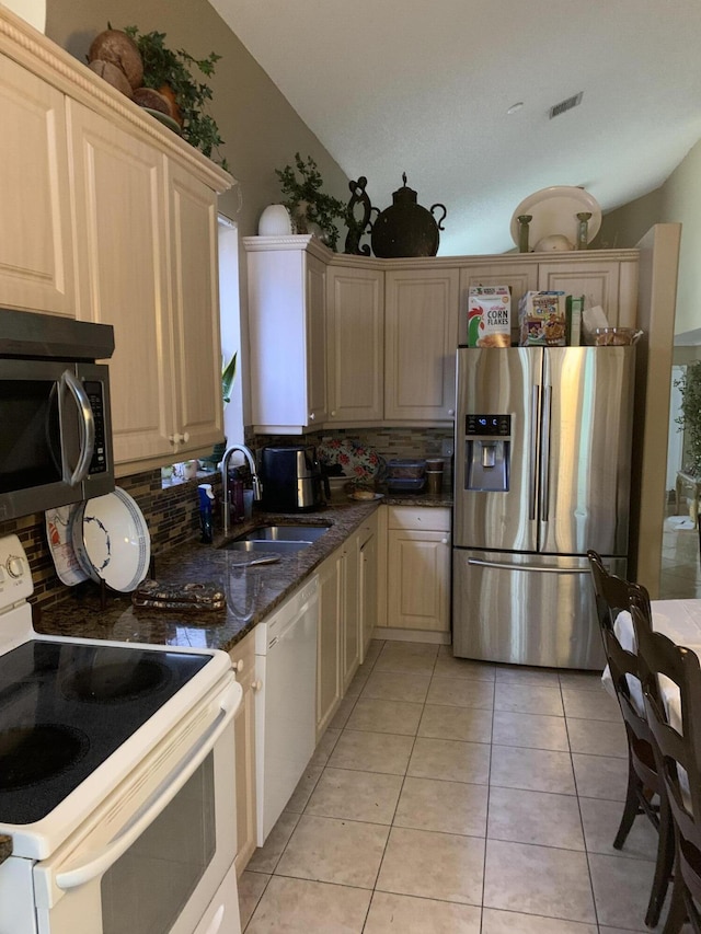 kitchen with white appliances, visible vents, light tile patterned flooring, a sink, and decorative backsplash