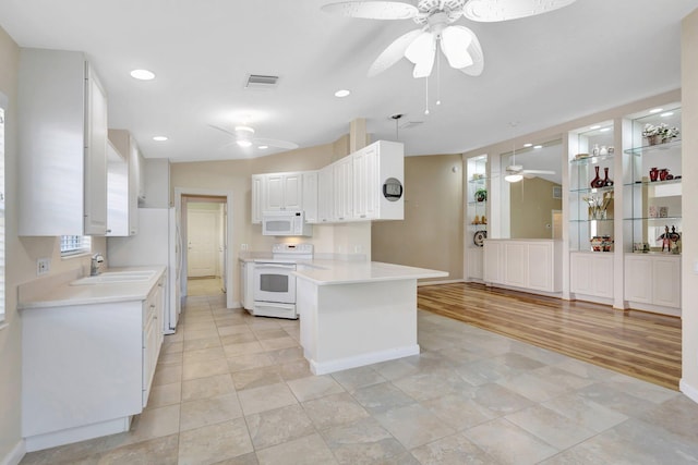 kitchen featuring visible vents, white cabinetry, white appliances, a peninsula, and light countertops