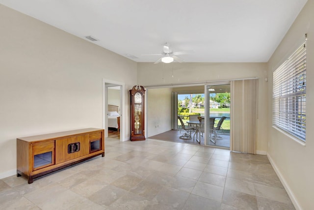 empty room with lofted ceiling, a ceiling fan, baseboards, and visible vents