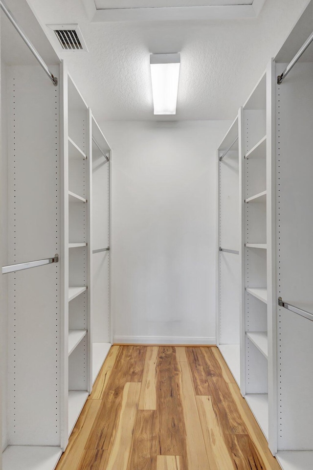 walk in closet with visible vents and wood finished floors