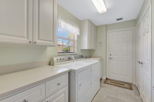 laundry room with light tile patterned flooring, visible vents, cabinet space, and washer and dryer