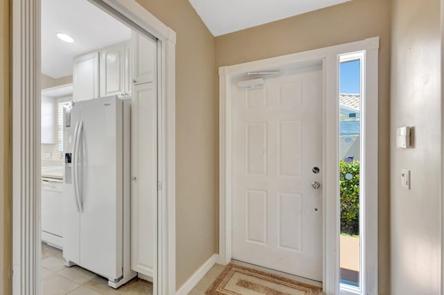 kitchen featuring white cabinetry, white appliances, light tile patterned floors, and baseboards