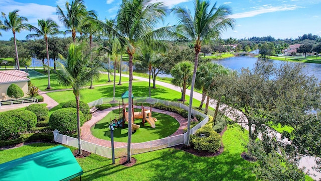 surrounding community with fence, a lawn, playground community, and a water view