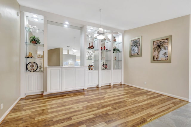 dining space with baseboards, light wood-style floors, built in shelves, and a ceiling fan