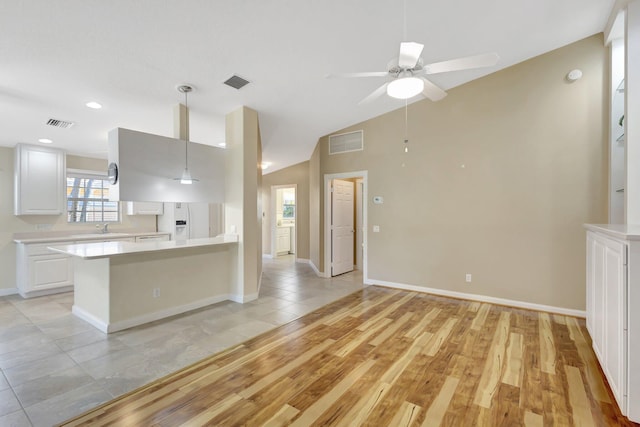 kitchen with visible vents, light wood finished floors, lofted ceiling, light countertops, and white cabinets