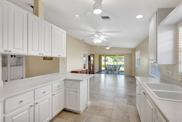 kitchen with a sink, visible vents, vaulted ceiling, and light countertops