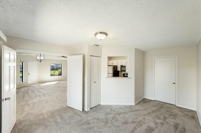 unfurnished room featuring baseboards, visible vents, a textured ceiling, and carpet