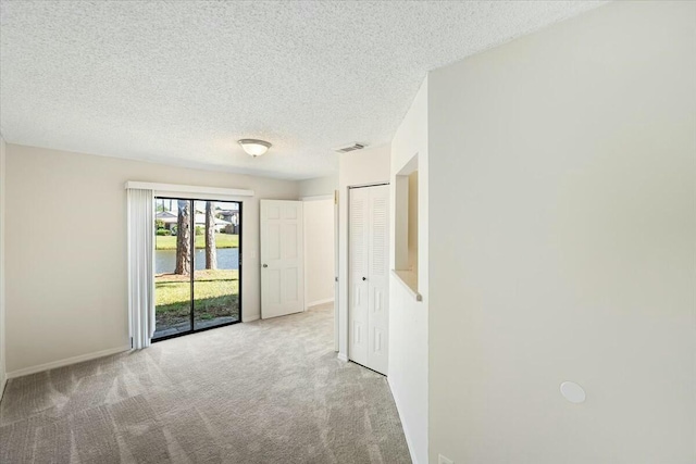 spare room with visible vents, baseboards, carpet, and a textured ceiling