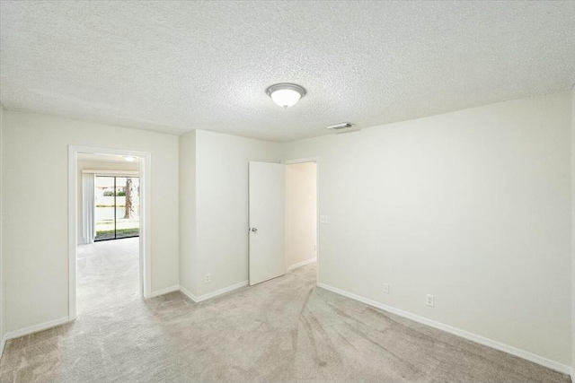 carpeted empty room featuring visible vents, baseboards, and a textured ceiling