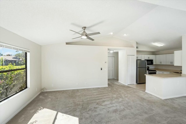 kitchen featuring black microwave, open floor plan, lofted ceiling, freestanding refrigerator, and a sink