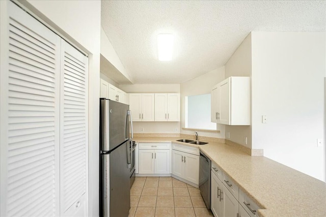 kitchen featuring light countertops, stainless steel appliances, a textured ceiling, white cabinetry, and a sink