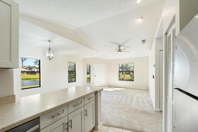 kitchen with freestanding refrigerator, vaulted ceiling, a textured ceiling, dishwasher, and light carpet