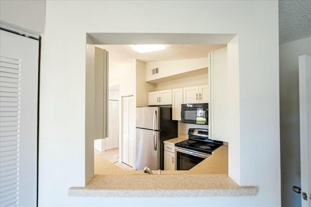 kitchen with visible vents, light countertops, vaulted ceiling, appliances with stainless steel finishes, and a textured ceiling