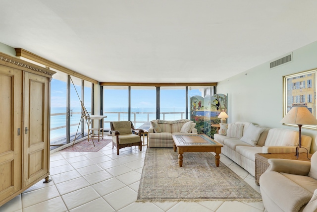 living room featuring light tile patterned floors, visible vents, a water view, and expansive windows