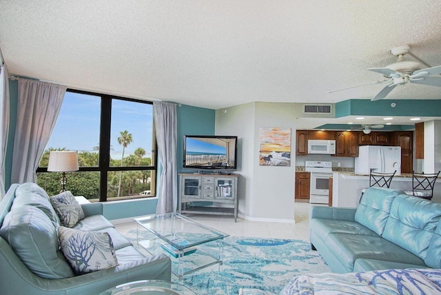 living room featuring light tile patterned flooring, a ceiling fan, visible vents, and a textured ceiling