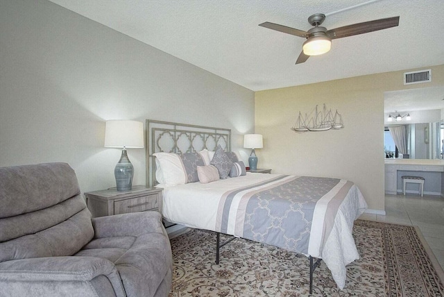 bedroom with tile patterned floors, a ceiling fan, visible vents, and a textured ceiling