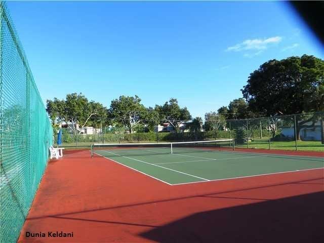 view of tennis court featuring community basketball court and fence