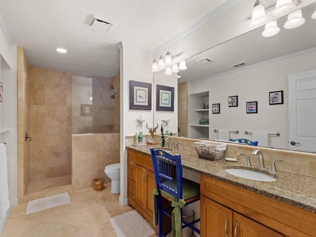 bathroom featuring visible vents, double vanity, ornamental molding, a sink, and a walk in shower