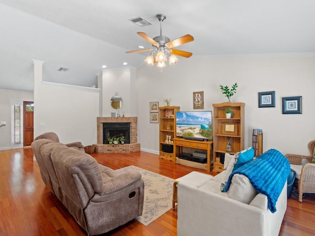 living area featuring visible vents, a brick fireplace, and wood finished floors