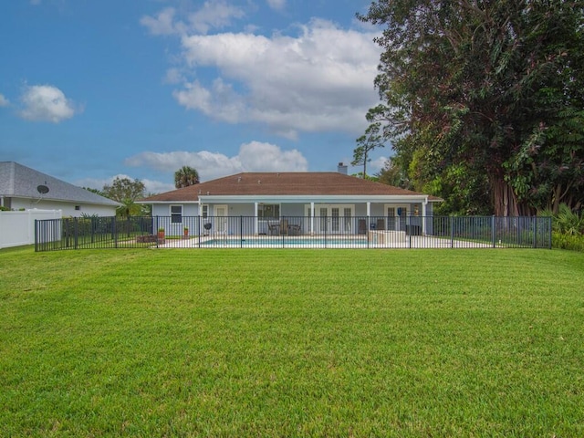 rear view of house with a fenced in pool, a lawn, and fence