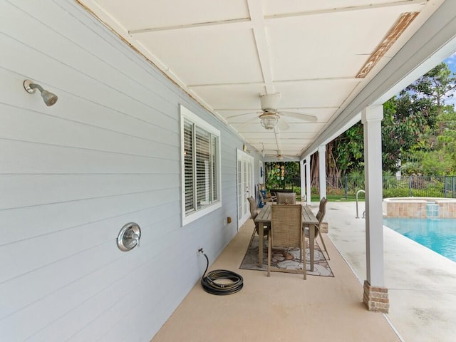 view of patio / terrace with an outdoor pool, an in ground hot tub, ceiling fan, and fence