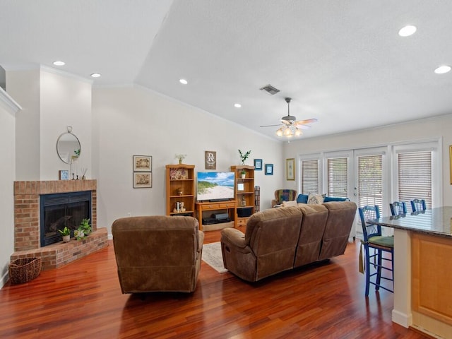 living room with ornamental molding, dark wood-style flooring, a fireplace, and vaulted ceiling