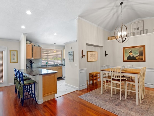 dining room featuring crown molding, light wood-style flooring, baseboards, and vaulted ceiling