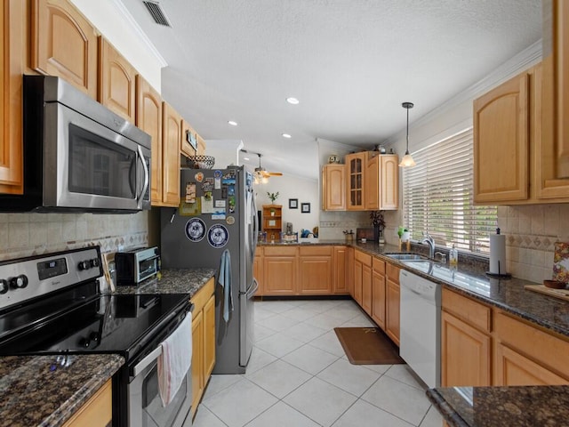 kitchen featuring visible vents, ornamental molding, dark stone countertops, appliances with stainless steel finishes, and light tile patterned floors