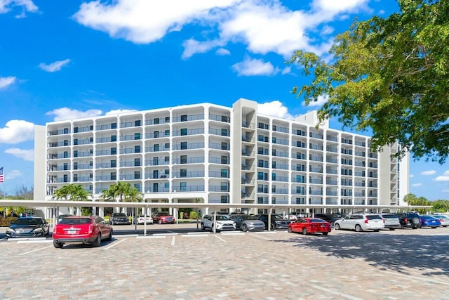 view of building exterior with covered and uncovered parking