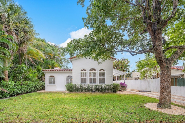 back of property featuring fence, a tiled roof, stucco siding, a lawn, and a pergola