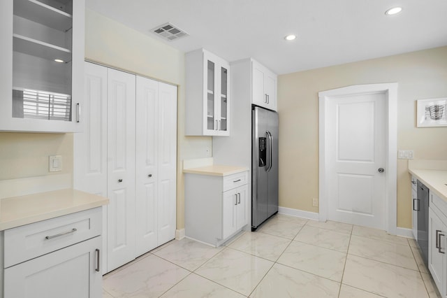 kitchen featuring glass insert cabinets, visible vents, stainless steel fridge, and marble finish floor