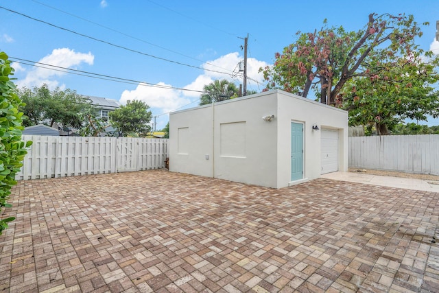 garage with decorative driveway and fence