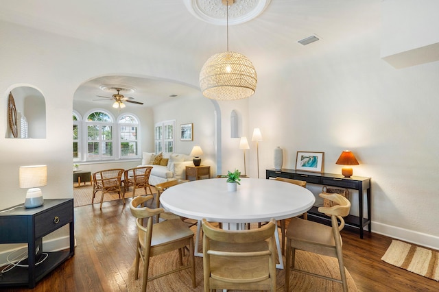 dining space featuring arched walkways, visible vents, wood-type flooring, and ceiling fan