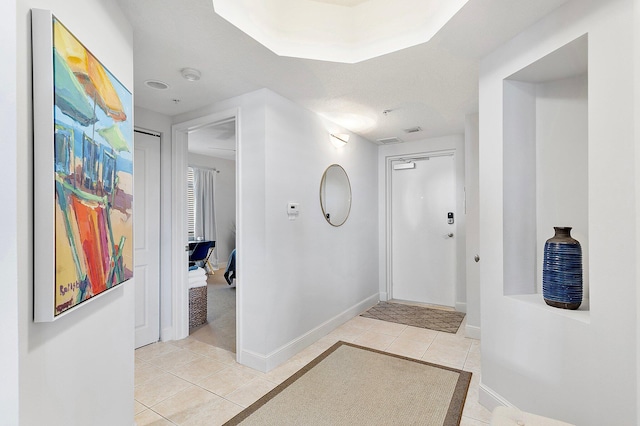 corridor with light tile patterned floors and baseboards