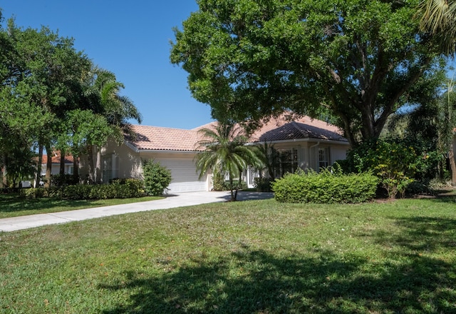 view of front of home with a front lawn, a tiled roof, stucco siding, a garage, and driveway