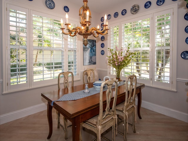 dining space featuring light wood-type flooring, baseboards, and a chandelier