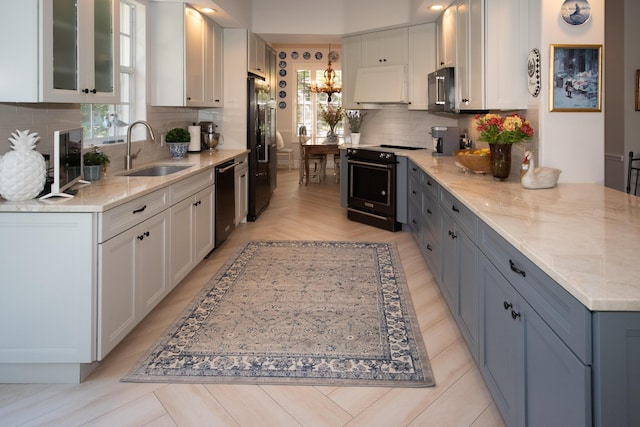 kitchen featuring a peninsula, a sink, black appliances, white cabinets, and backsplash