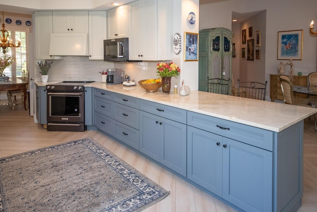 kitchen with electric stove, tasteful backsplash, a peninsula, black microwave, and a chandelier