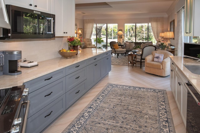 kitchen with decorative backsplash, crown molding, light stone counters, and open floor plan