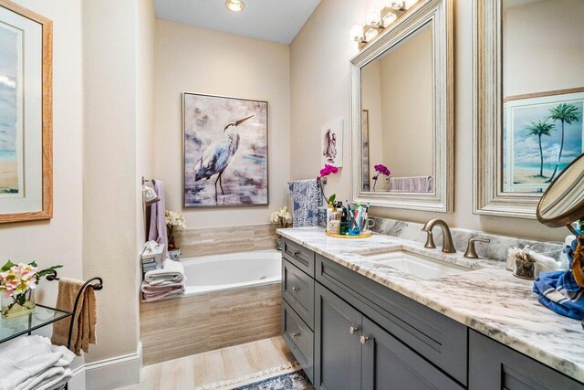 396 Kelsey Park Dr, Palm Beach Gardens, FL 33410 - bathroom featuring vanity, a garden tub, and wood finished floors