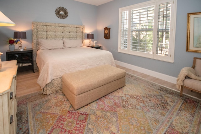 bedroom with baseboards, multiple windows, and wood finished floors