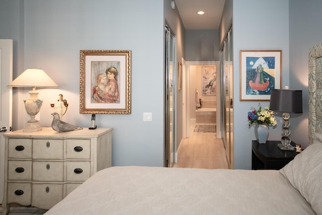 bedroom with ensuite bath and light wood-type flooring